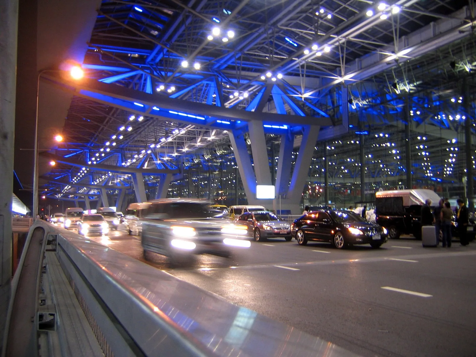 Vehicles approaching the illuminated passenger terminal at Suvarnabhumi Airport